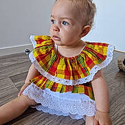 Leya a rejoint le concours — aidez-le/la à gagner de superbes lots ! blue_eyes, child, curly_hair, cute, floor, foot, green, hand, indoor, lace, person, plaid_dress, portrait, red, sitting, skin, toddler, wooden_floor, yellow, young_child