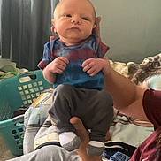 Leo joined the competition — help win amazing prizes! baby, infant, person, clothing, tie_dye, socks, pants, hand, adult, furniture, blanket, laundry_basket, curtains, indoor, casual, seated, portrait, home, relaxed, cozy