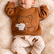 Mavis is registered to the contest to win money with this photo: baby, infant, child, cute, fox, brown_sweater, patterned_pants, soft_blanket, cozy, smiling, lying_down, warm_clothing, happy, indoors, portrait, small_feet, baby_socks, toddler, soft_texture, comfortable