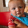 baby, child, burger_king, crown, red_shirt, striped_clothing, hand, adult_hand, fast_food, restaurant, booth, table, blue_bib, face, skin, portrait, indoor, seated, cute, expression