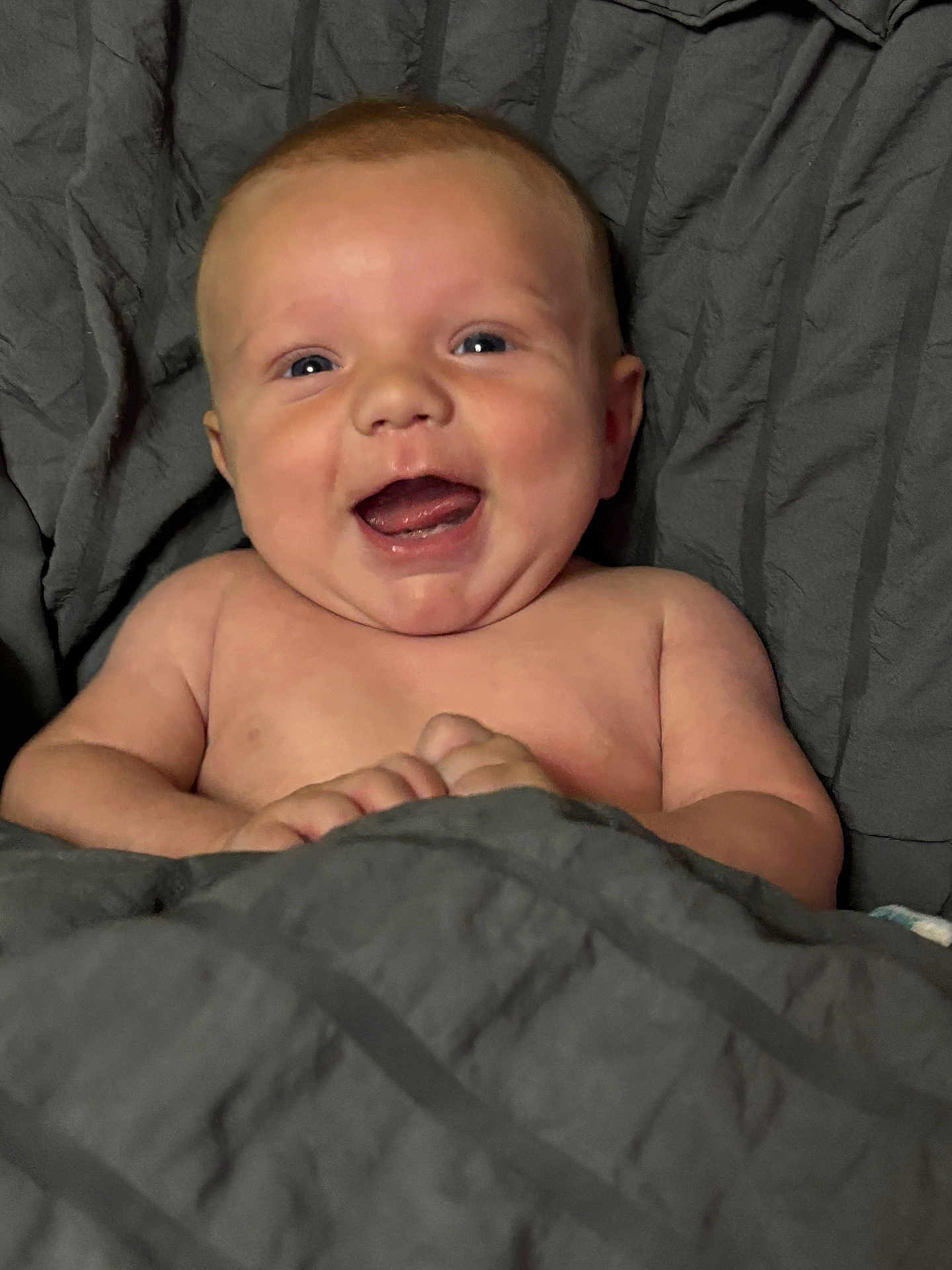 Thomas is registered to the contest to win money with this photo: baby, smiling, happy, infant, blanket, face, skin, cheeks, hands, lying_down, cozy, comfort, cute, young_child, portrait, expression, indoors, warm, human, child