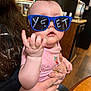 adult, baby, blue_glasses, cabinet, child, curious, cute, expression, eyewear, face, hand, holding, indoor, kitchen, long_hair, person, pink_shirt, sunglasses, table, wood_floor