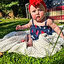 Hailey joined the competition — help win amazing prizes! american_flag, baby, blanket, blue, child, curious, expression, face, grass, headband, nature, outdoor, patterned_clothing, portrait, red, sitting, summer, sunlight, white, wooden_background