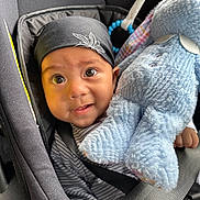 Robin is registered to the contest to win money with this photo: baby, infant, car_seat, bandana, stuffed_animal, toy, blue, black, clothing, child, cute, face, headwear, seatbelt, closeup, expression, indoor, person, portrait, young_child