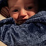 baby, infant, child, face, eyes, cheeks, blanket, towel, hood, blue_towel, cozy, close_up, portrait, indoor, hand, soft_texture, adorable, gaze, warm_lighting, snuggle