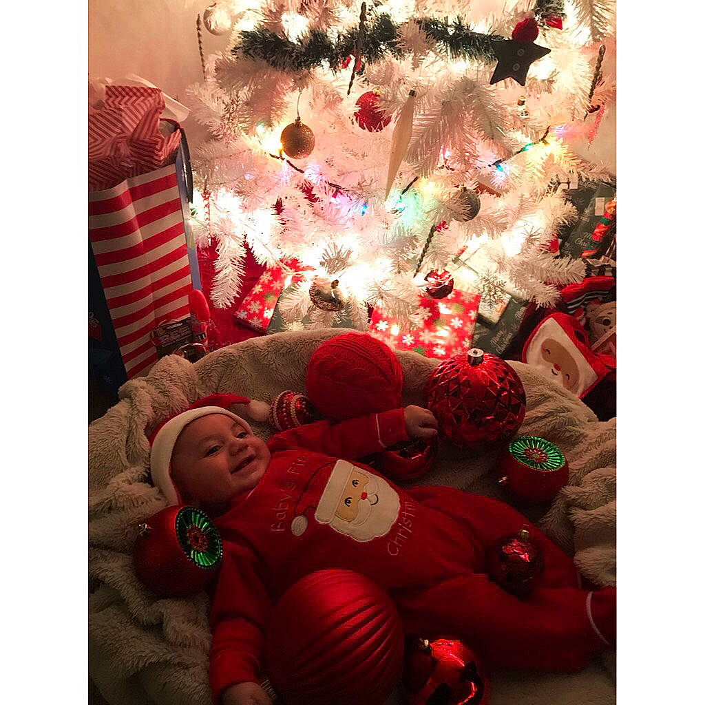 Luka is registered to the contest to win money with this photo: baby, baby_toddler_clothing, christmas, christmas_decoration, christmas_eve, christmas_ornament, christmas_tree, comfort, conifer, event, happy, headwear, holiday, holiday_ornament, joy, lap, magenta, ornament, person, red