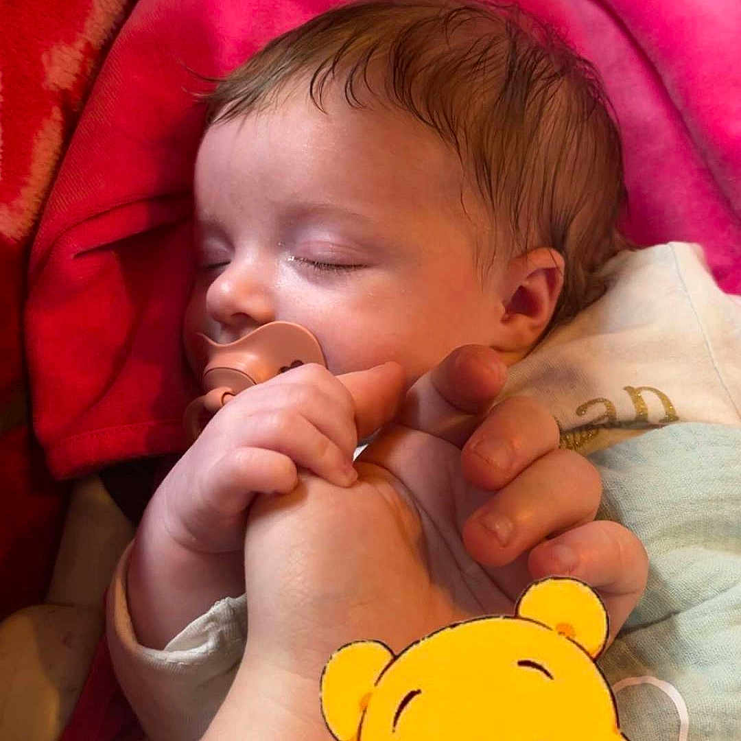 Lylo participe au concours pour gagner de l'argent avec cette photo : baby, bedding, blanket, cartoon_sticker, child, close_up, cozy, cuteness, hair, hand_holding, infant, nursery, pacifier, peaceful, pink_blanket, portrait, red_blanket, skin, sleeping, winnie_the_pooh