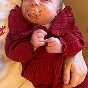 Lylo a rejoint le concours — aidez-le/la à gagner de superbes lots ! baby, infant, pacifier, red_dress, hands, adult_hand, tattoo, blanket, close_up, portrait, indoor, skin, face, cute, ruffled_collar, leg_warmers, sitting, comfort, toy, smiling