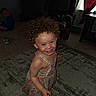 barefoot, boy, carpet, child, curly_hair, curtain, curtains, dress, furniture, happy, home, indoor, living_room, person, playful, rug, sitting, smiling, toddler, window
