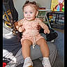 Neveah is registered to the contest to win money with this photo: adult, carpet, cartoon, casual, child, curly_hair, cute, furniture, happy, high_chair, home, indoor, lap, living_room, person, romper, sitting, television, toddler, white_shoes