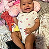 baby, blanket, carpet, child, clothes, cute, face, happy, indoor, infant, lying_down, onesie, person, pillow, pink, playful, skin, smiling, toddler, watermelon_pattern