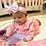 baby, infant, pink_outfit, headband, bow, blanket, floral_pattern, crib, floor, crawling, child, cute, smiling, indoors, soft_lighting, portrait, toddler, happy, person, clothing