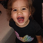 Luna joined the competition — help win amazing prizes! child, toddler, smiling, barefoot, indoor, carpet, couch, shirt, barbie, happy, person, face, hair, mouth_open, teeth, eyes, clothing, standing, home, cute
