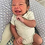 baby, infant, smiling, happy, onesie, socks, cushion, polka_dot, face, hand, foot, skin, person, newborn, cute, indoors, portrait, child, seated, cozy