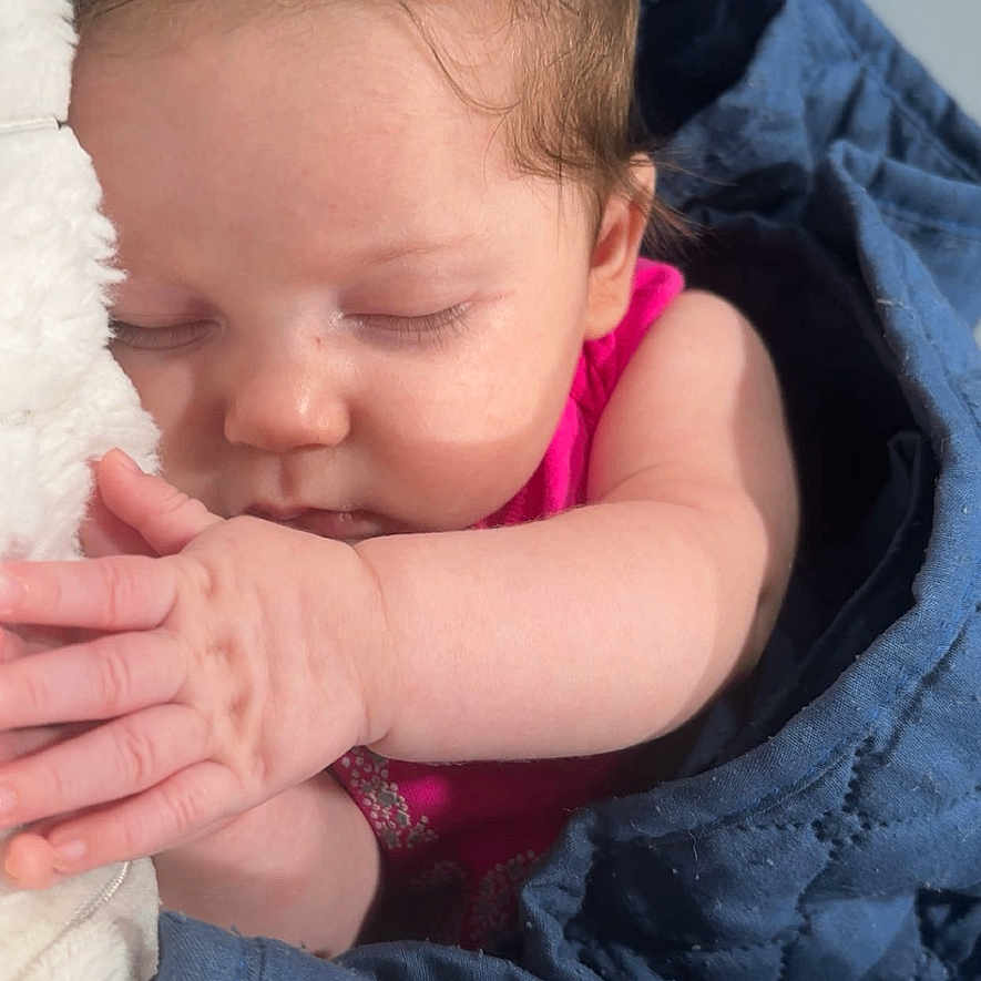 Ecxo is registered to the contest to win money with this photo: baby, blanket, blue, child, closeup, cozy, cute, face, hair, hand, indoors, infant, peaceful, pink_clothing, portrait, relaxation, rest, skin, sleeping, soft_light