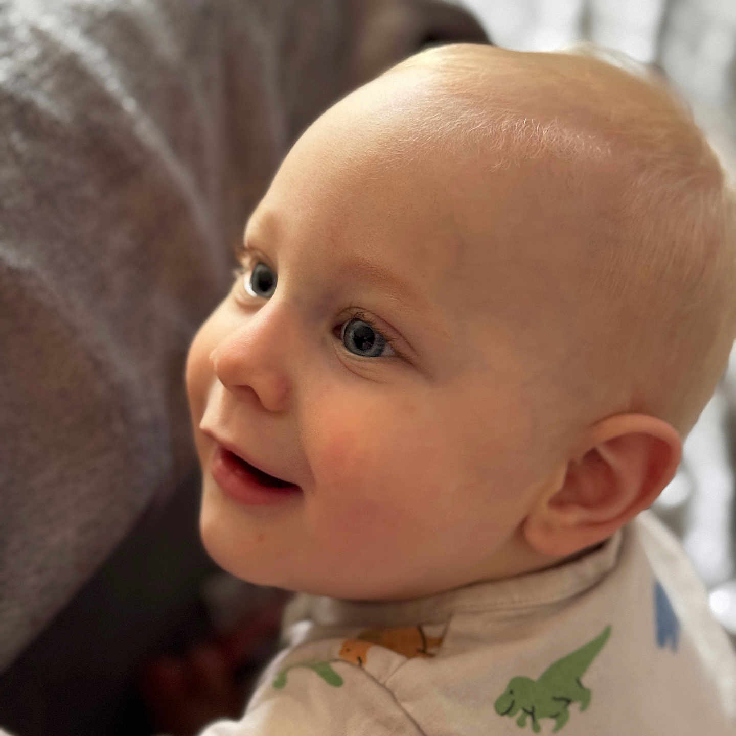 Emmett a rejoint le concours — aidez-le/la à gagner de superbes lots ! baby, blond_hair, blue_eyes, cheek, child, closeup, curious, cute, dinosaur_print, ear, face, happy, indoors, infant, onesie, person, portrait, skin, smile, soft_light