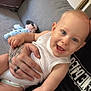 arm, baby, blue_eyes, child, couch, cute, diaper, face, hand, happy, holding, indoor, mickey_mouse, person, plush_toy, sitting, skin, smiling, tattoo, white_clothing