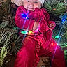 Harmony joined the competition — help win amazing prizes! baby, infant, child, santa_hat, christmas, christmas_tree, holiday, festive, red_outfit, smiling, face, portrait, indoors, ornaments, string_lights, colorful_lights, pine_branches, holiday_decoration, sitting, happy