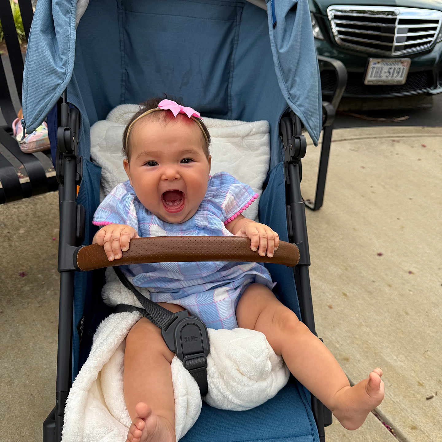 Amina joined the competition — help win amazing prizes! baby, blanket, blue, car, child, clothing, expression, foot, grip, hand, happy, headband, outdoor, person, pink_bow, seatbelt, sidewalk, smiling, stroller, transport