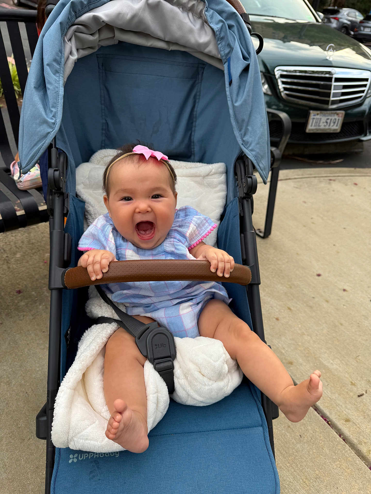 Amina joined the competition — help win amazing prizes! baby, stroller, blue, pink_bow, blanket, smiling, happy, outdoor, sidewalk, car, seatbelt, child, person, clothing, foot, hand, headband, grip, expression, transport
