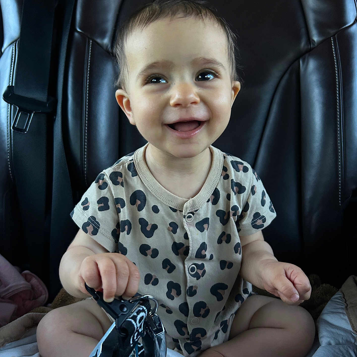 Angel participe au concours pour gagner de l'argent avec cette photo : baby, car_seat, child, clothing, cute, expression, feet, hands, happy, indoor, infant, keys, leopard_print, onesie, person, portrait, seatbelt, sitting, smiling, young_child