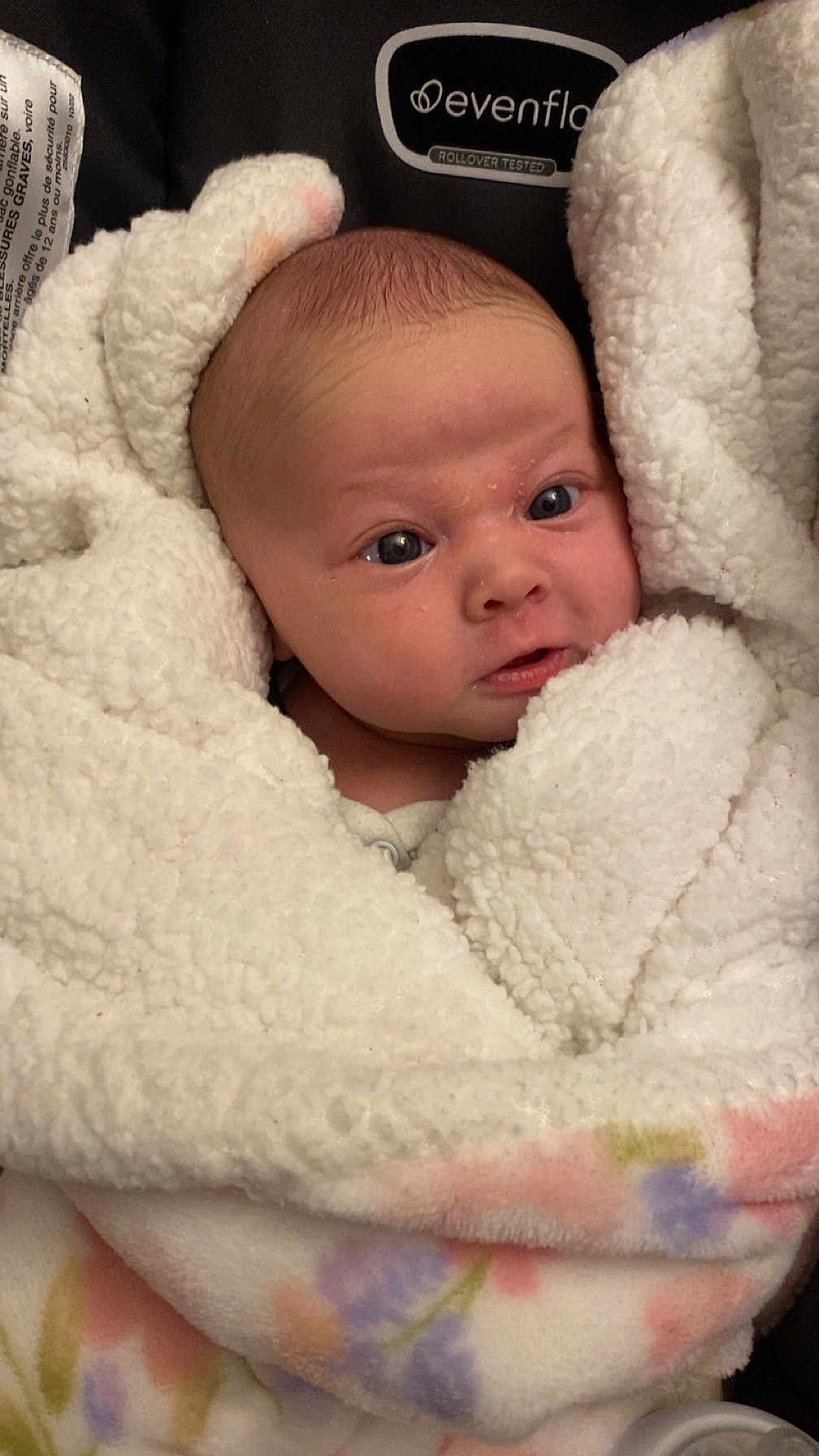 Lilli is registered to the contest to win money with this photo: baby, newborn, blanket, swaddled, car_seat, infant, face, eyes, soft_texture, clothing, fluffy, pastel_colors, pattern, person, child, cute, indoors, closeup, head, portrait