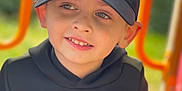 Tyago participe au concours pour gagner de l'argent avec cette photo : child, boy, cap, hoodie, smile, face, outdoor, playground, park, clothing, person, happy, casual, young, headwear, green, orange, daylight, cute, portrait