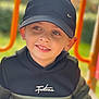 child, boy, cap, hoodie, smile, face, outdoor, playground, park, clothing, person, happy, casual, young, headwear, green, orange, daylight, cute, portrait