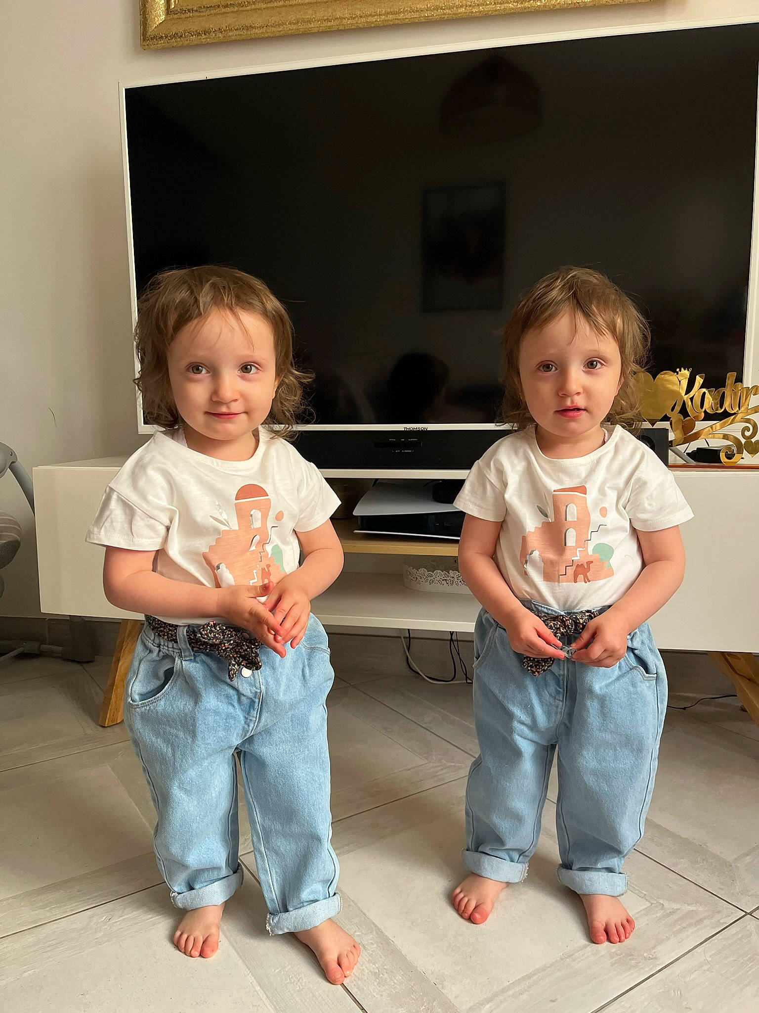 Assia Et Leyla a rejoint le concours — aidez-le/la à gagner de superbes lots ! baby_toddler_clothing, barefoot, child, clothing, comfort, denim, floor, flooring, fun, gesture, happy, jeans, joy, leisure, person, picture_frame, shoulder, sitting, smile, t_shirt