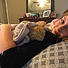 girl, cat, blanket, bedroom, pillow, resting, sleeping_cat, smiling, indoor, furniture, mirror, photograph, portrait, relaxation, home, comfort, child, animal, soft, warm