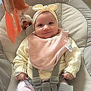 Mayna participe au concours pour gagner de l'argent avec cette photo : baby, baby_seat, bib, child, clothing, comfort, cushion, cute, happy, headband, indoor, infant, pattern, person, pink, smile, soft_toy, straps, toy, yellow