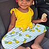 Tianna joined the competition — help win amazing prizes! child, girl, smiling, braids, beads, yellow_top, pineapple_skirt, cookie, car_seat, barefoot, happy, cute, portrait, indoors, seatbelt, clothing, food, snack, person, hair_accessories