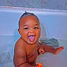 baby, bathtub, water, toy, smiling, child, bath, happy, playful, indoor, tiled_wall, skin, face, hand, foot, hair, orange_toy, heart_emoji, bathroom, cute