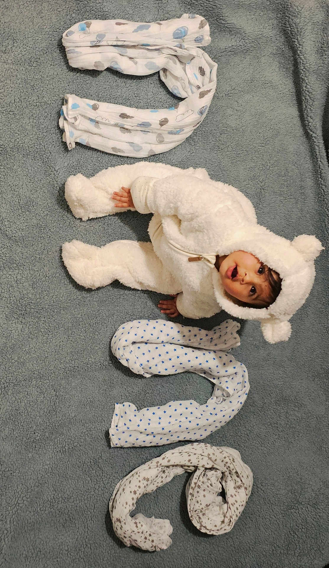 Gatha a rejoint le concours — aidez-le/la à gagner de superbes lots ! baby, bear_costume, blanket, child, cozy, creative_arrangement, curious, cute, expression, fluffy_suit, gray_background, indoors, infant, lying_down, number, patterned_blankets, portrait, rolled_blankets, soft_texture, warm_clothing