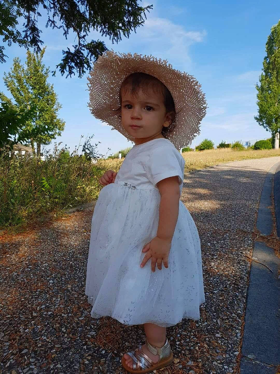 Lya a rejoint le concours — aidez-le/la à gagner de superbes lots ! child, clothing, dress, fashion_accessory, hat, head, headgear, outerwear, person, photograph, photography, smile, standing, summer, toddler, tree, trunk
