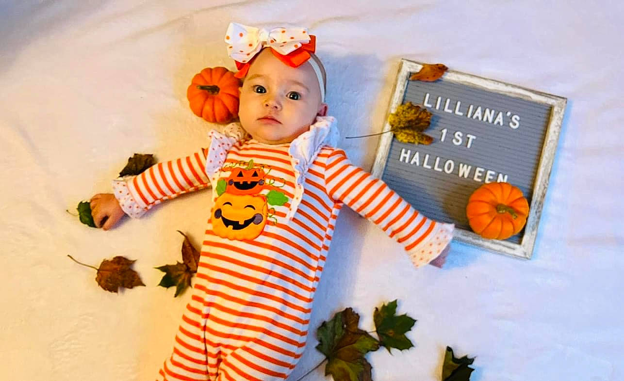 Lilliana is registered to the contest to win money with this photo: baby, baby_toddler_clothing, baby_toys, child, doll, font, happy, headwear, linens, natural_foods, orange, pattern, person, plant, product, room, sleeve, stuffed_toy, t_shirt, toddler