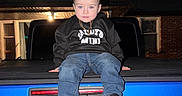 Luis is registered to the contest to win money with this photo: toddler, child, jeep, blue_vehicle, night, braided_hair, hoodie, sneakers, gold_chain, jeans, sitting, vehicle, outdoor, portrait, face, flash_photo, casual_clothing, urban, young_child, expressionless