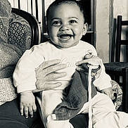 Wilson participe au concours pour gagner de l'argent avec cette photo : baby, smile, infant, pacifier, hand, clothing, person, indoor, furniture, chair, couch, blanket, portrait, happy, sitting, black_and_white, toy, holding, face, expression