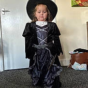 Bonnie joined the competition — help win amazing prizes! child, witch_costume, black_hat, black_dress, indoor, carpet, door, bag, diapers, portrait, person, wall_art, standing, young_child, costume, dress_up, room, floor, photograph, hat