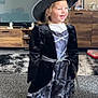 Bonnie is registered to the contest to win money with this photo: child, costume, witch_hat, dress, smiling, indoor, carpet, living_room, furniture, television, wooden_cabinet, toy_box, happy, portrait, person, clothing, home, blonde_hair, floor, decor
