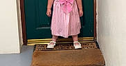 Bonnie-Leigh is registered to the contest to win money with this photo: child, girl, toddler, smiling, portrait, standing, dress, pink_dress, striped_dress, bow, sandals, door, front_door, doorway, doormat, hallway, home, indoors, full_body, photograph