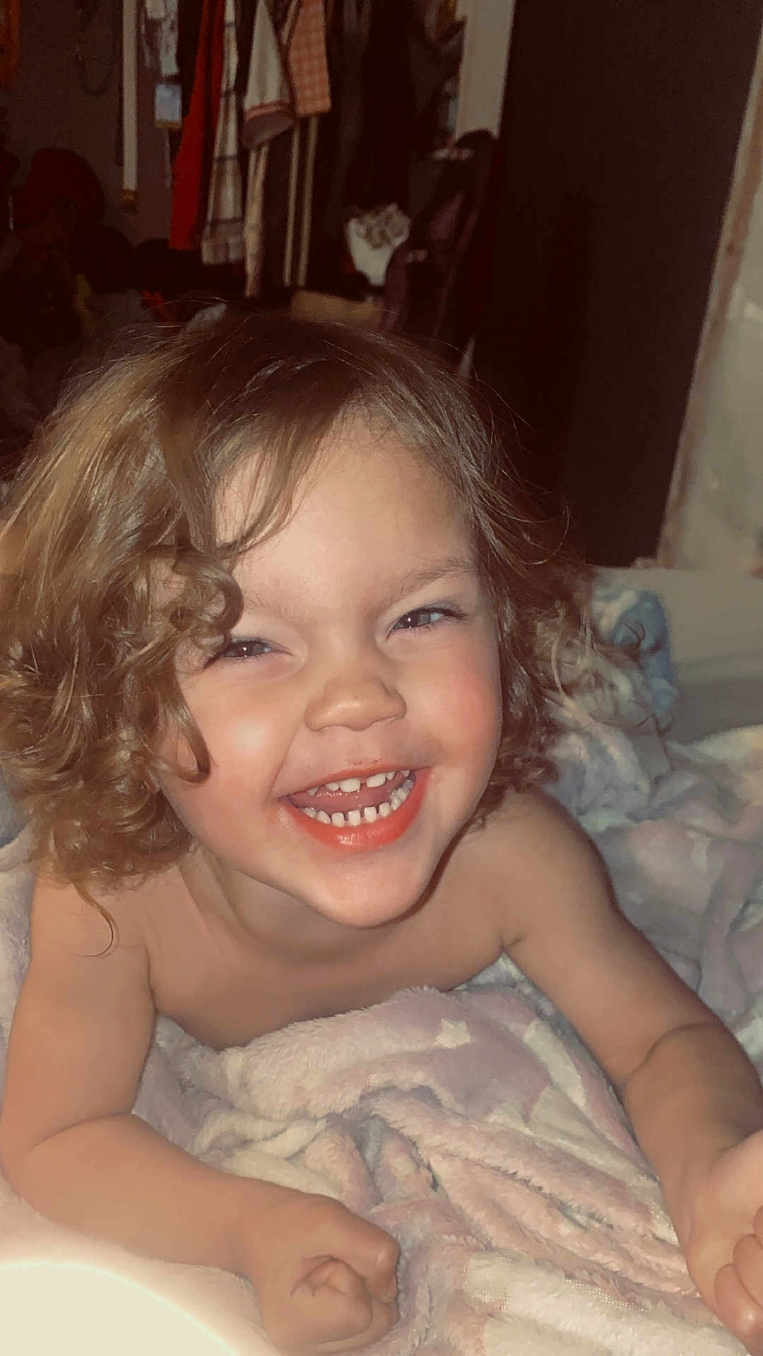 Gunnar joined the competition — help win amazing prizes! child, toddler, curly_hair, smile, laughing, teeth, blanket, bed, indoor, portrait, closeup, happy, cozy, bare_shoulders, skin, candid, bedroom, clothing_hanging, playful, infant