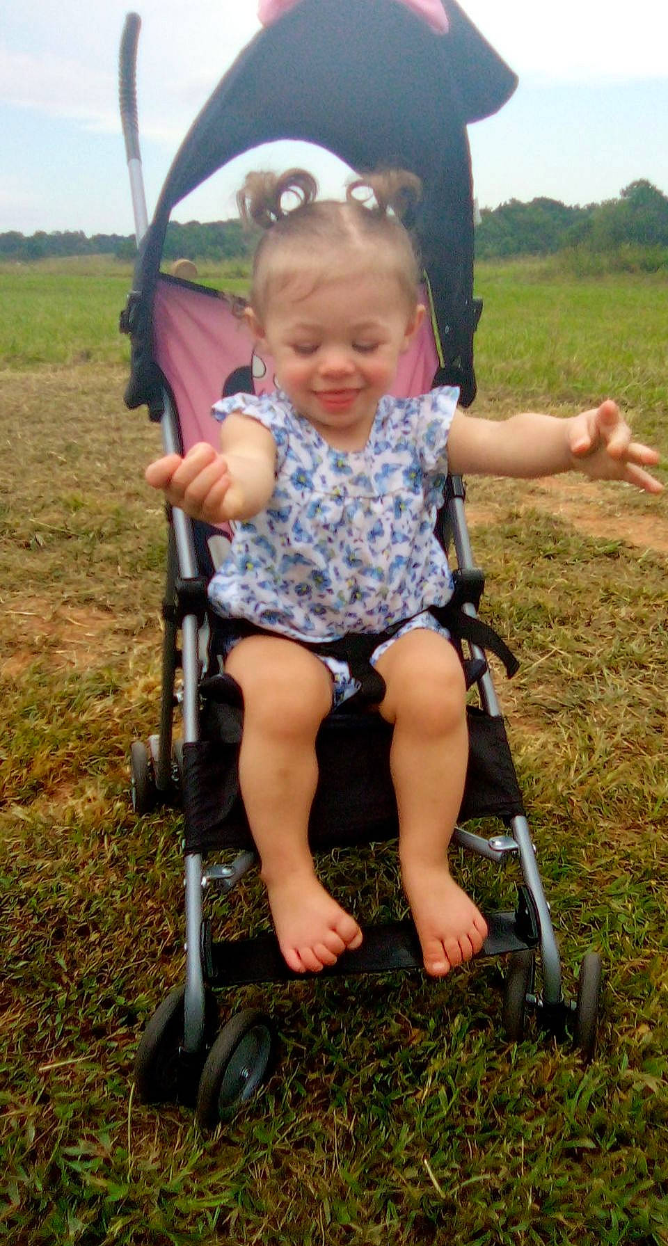 Barbara is registered to the contest to win money with this photo: baby_carriage, baby_products, bicycle_accessory, child, eye, fun, grass, grassland, happy, joy, leisure, people_in_nature, person, plant, recreation, sitting, sky, snapshot, summer, tire