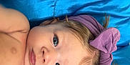 Ava is registered to the contest to win money with this photo: baby, background, blue_eyes, bow, child, closeup, cute, expression, fabric, face, headband, indoors, infant, lying_down, person, portrait, purple, skin, soft, young
