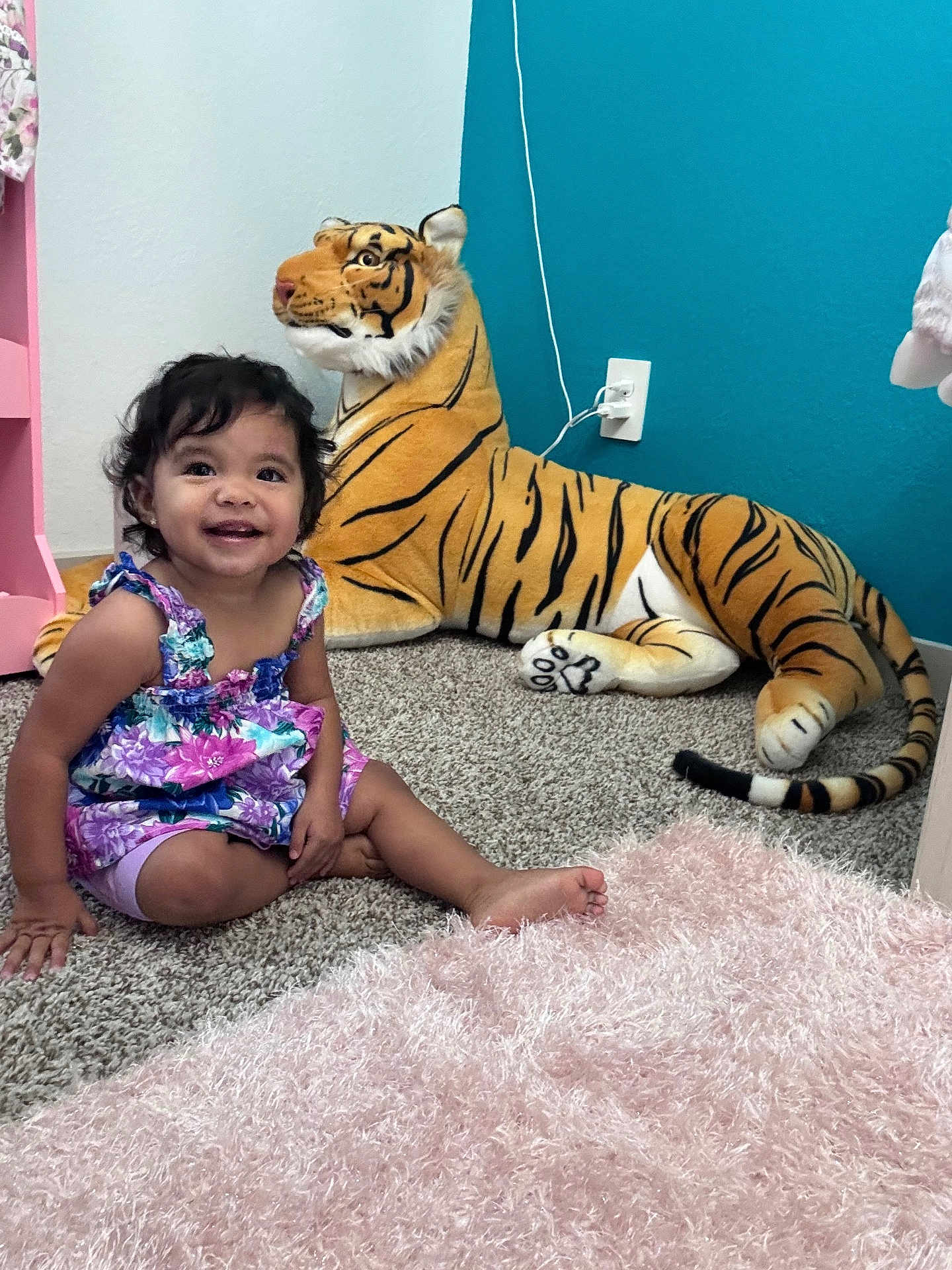 Jasmine joined the competition — help win amazing prizes! child, toddler, smiling, sitting, plush_toy, tiger, carpet, indoor, colorful_clothing, furniture, wall, pink, blue, toy, cute, happy, room, hair, person, floor