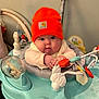Charlee is registered to the contest to win money with this photo: baby, infant, beanie, orange_hat, activity_center, bouncer, chubby_cheeks, blue_eyes, hands, tongue, toy, plastic_toy, seat, indoor, nursery, clothing, cute, portrait, playtime, parenting