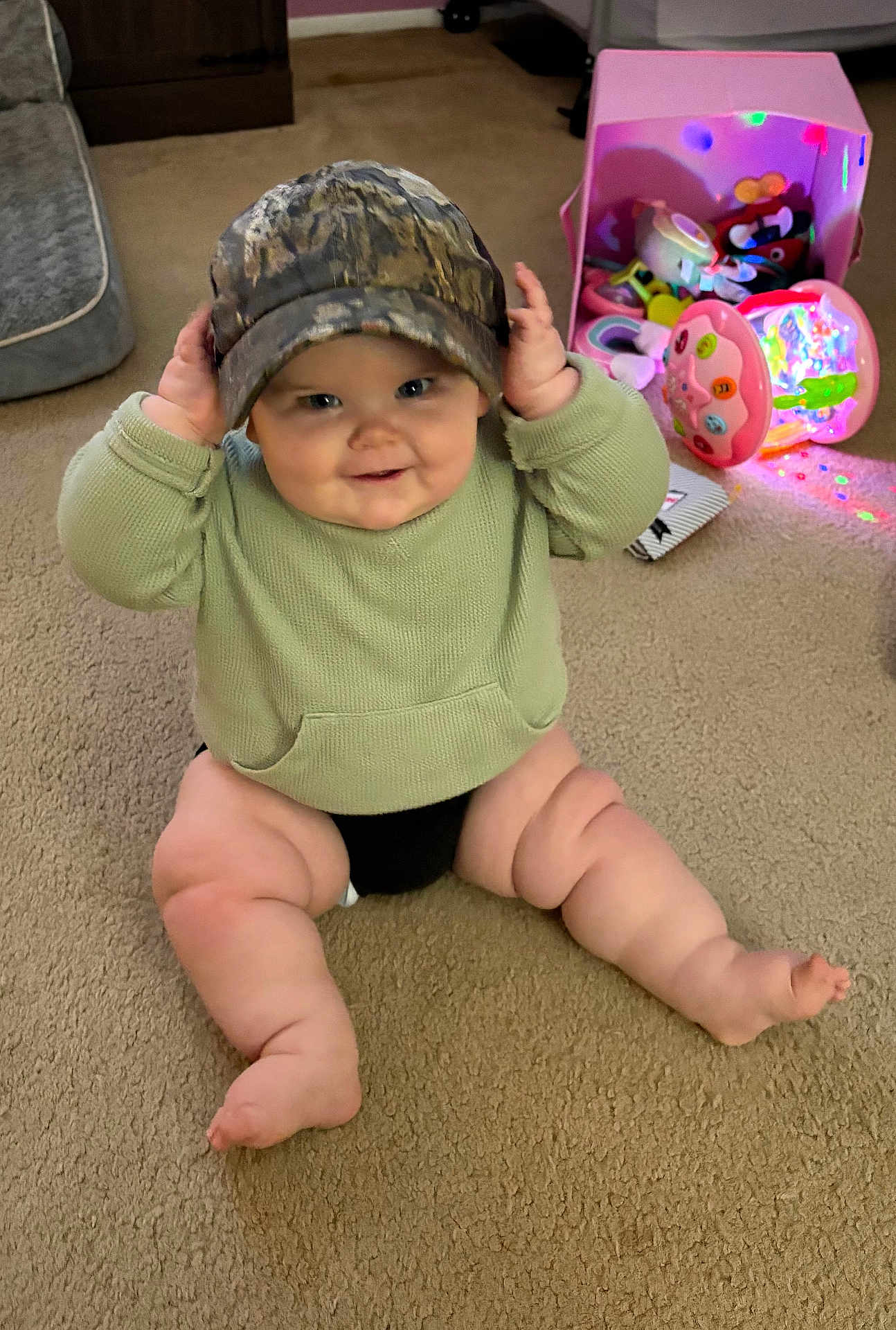 Charlee joined the competition — help win amazing prizes! baby, infant, hat, camouflage, sweater, sitting, carpet, toys, toy_box, colorful_lights, smile, chubby_legs, hands, playtime, indoor, candid, portrait, barefoot, cozy, nursery
