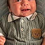baby, smiling, infant, knitted_clothing, teddy_bear_patch, cute, happy, portrait, child, cozy, buttoned_shirt, texture, soft_blanket, closeup, young_child, face, hand, casual, indoors, cute_expression