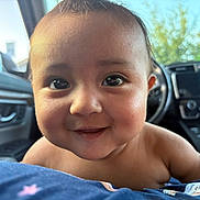 Gabriela is registered to the contest to win money with this photo: baby, child, face, smile, eyes, car_interior, steering_wheel, dashboard, close_up, portrait, happy, cute, skin, infant, indoors, seat, clothing, human, person, expression