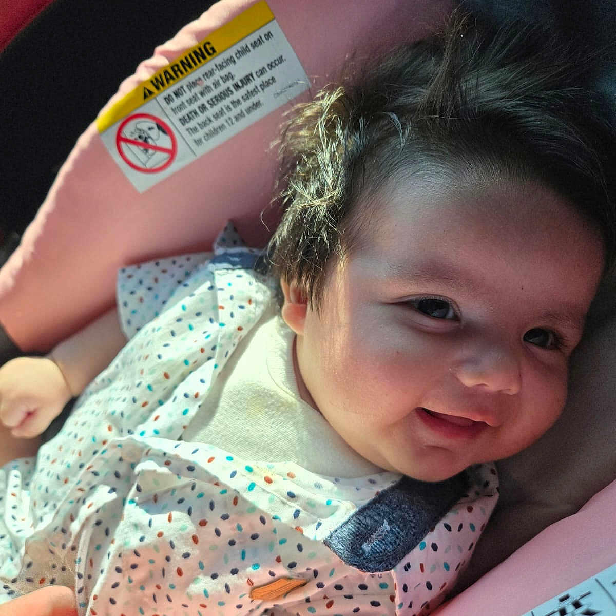 Mati is registered to the contest to win money with this photo: baby, car_seat, child, clothing, comfort, cute, dotted_pattern, face, hair, hand, indoors, infant, light, person, pink, portrait, seat, skin, smile, young